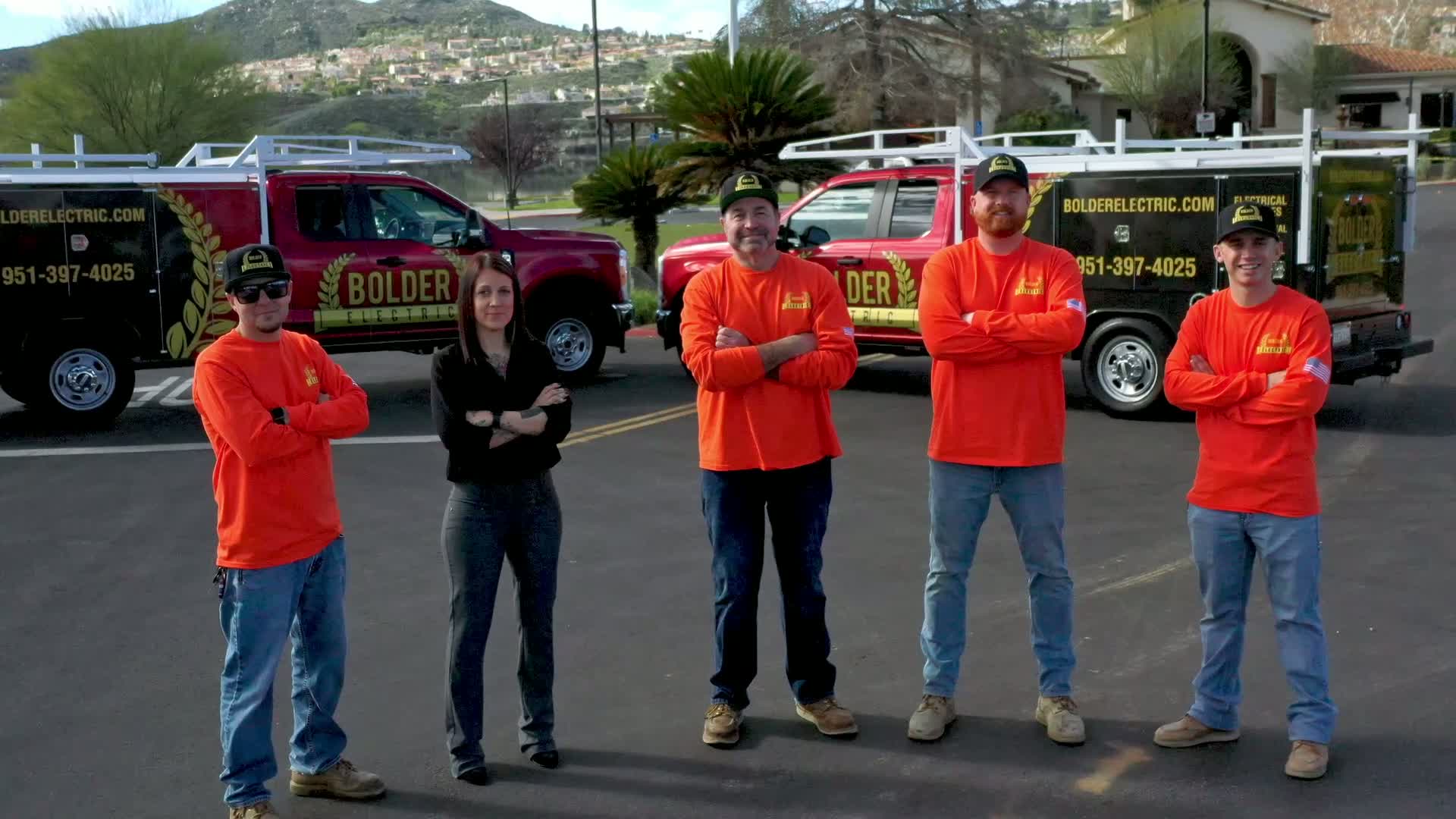 Bolder Electric team standing with company vehicles